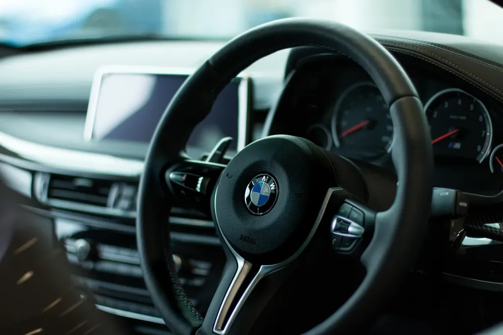 Nowoczesne wnętrze samochodu BMW z widoczną kierownicą i deską rozdzielczą.